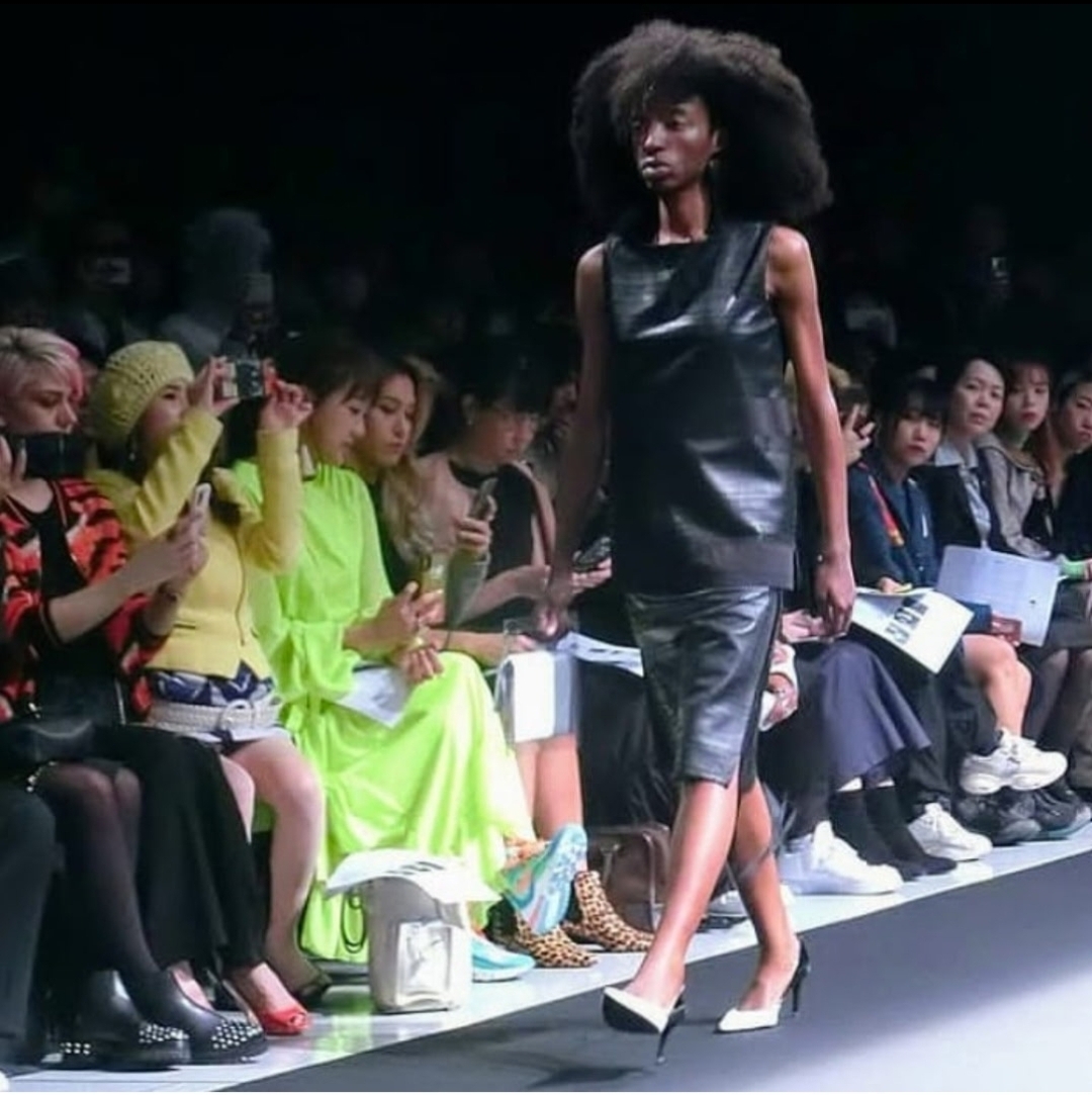 Arziki on fashion runway in black leather dress